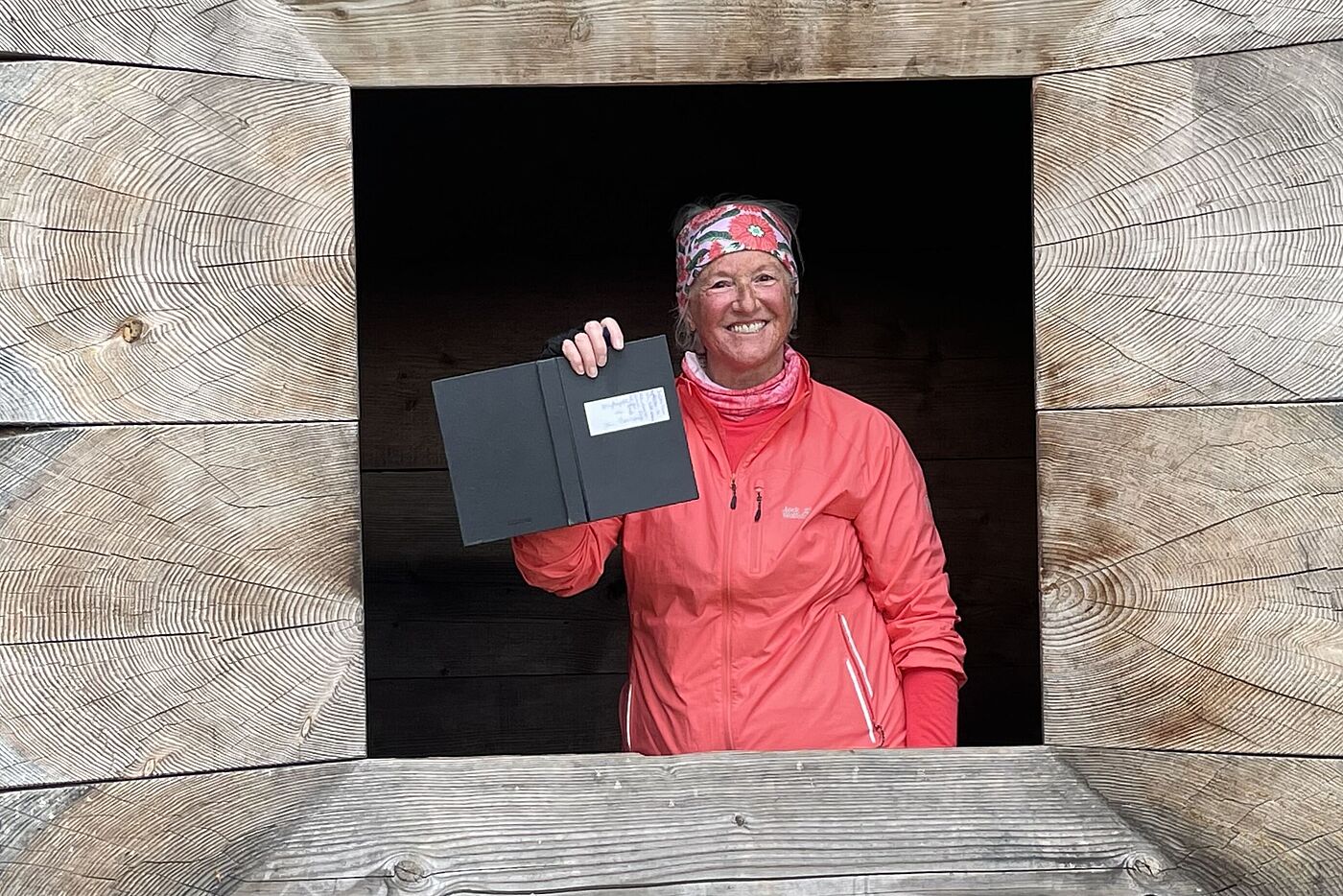 Frau blickt aus Blockhaus-Fenster