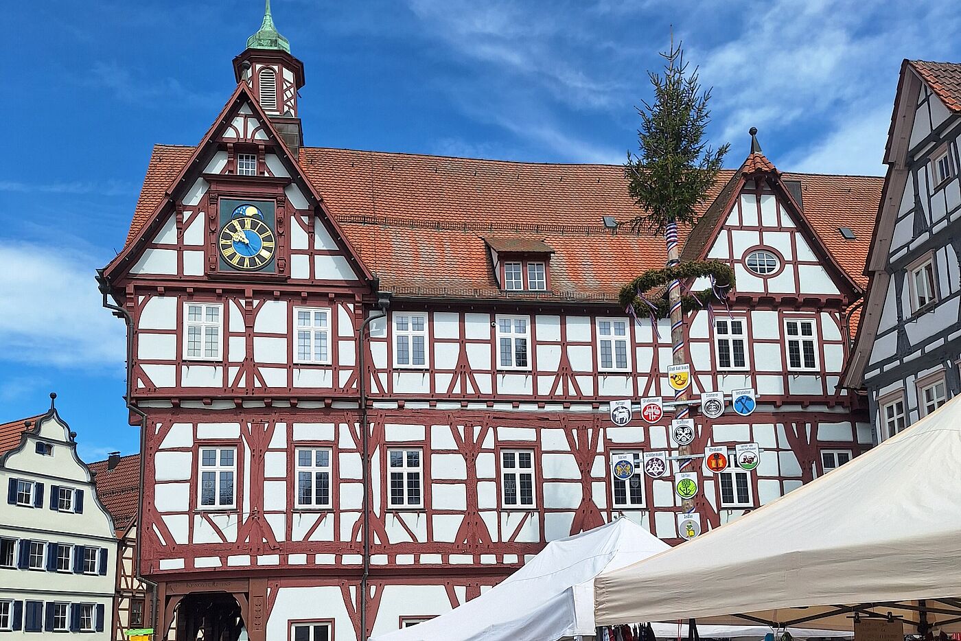 Fachwerkhaus mit Uhr, davor Markt