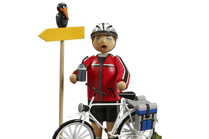 Symbol_Radfahrerin Käthe-Wohlfahrt-Figur eines Radfahrers auf Tour mit Wegweiser