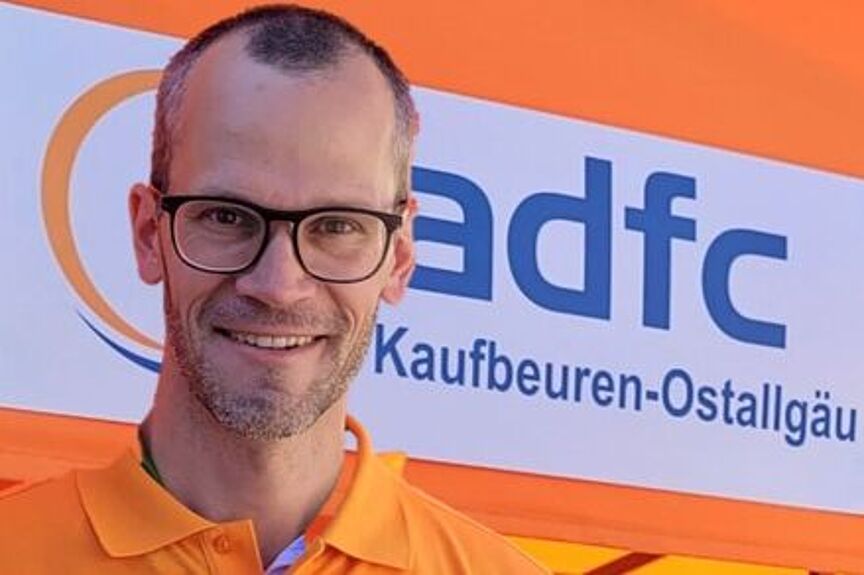 Johannes Auburger Mann mit orangenem Poloshirt vor ADFC-Banner