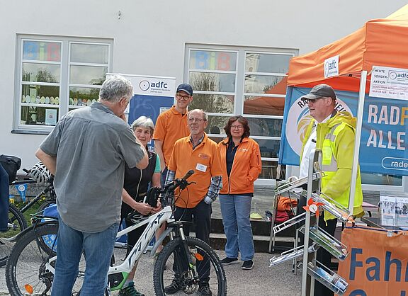 Rad, Infostand und Erwachsene im Gespräch