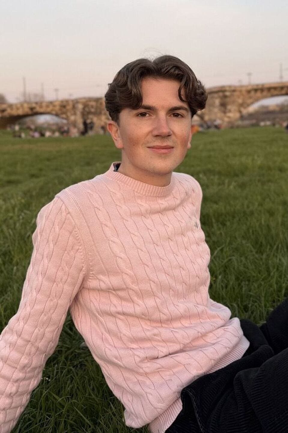 Jonas Müller junger Mann auf Wiese vor Brücke